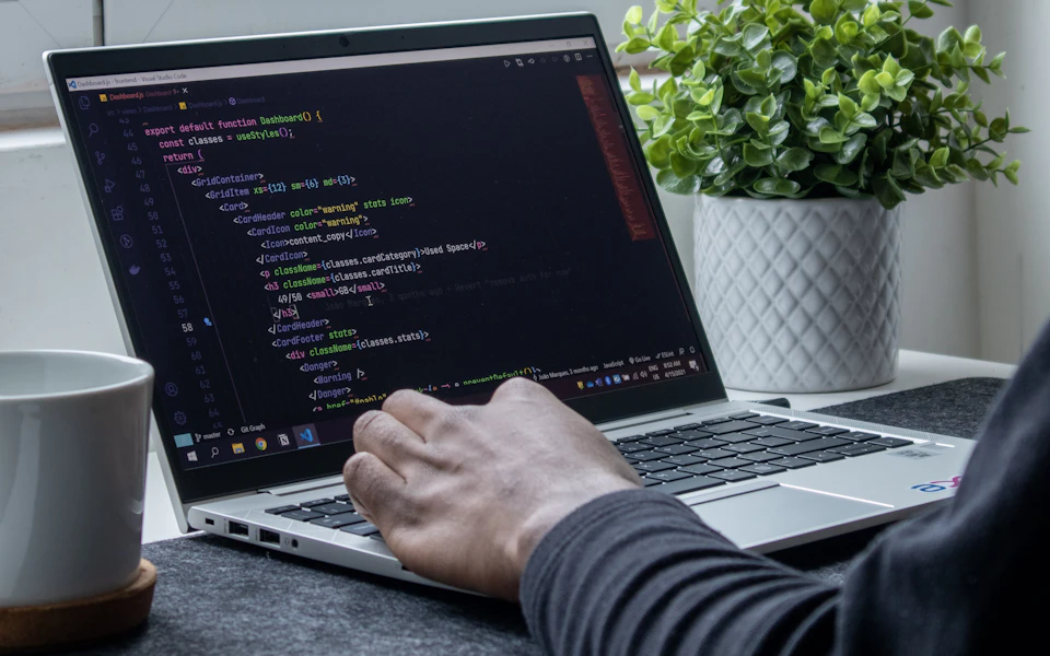 Hands working on application code on a laptop